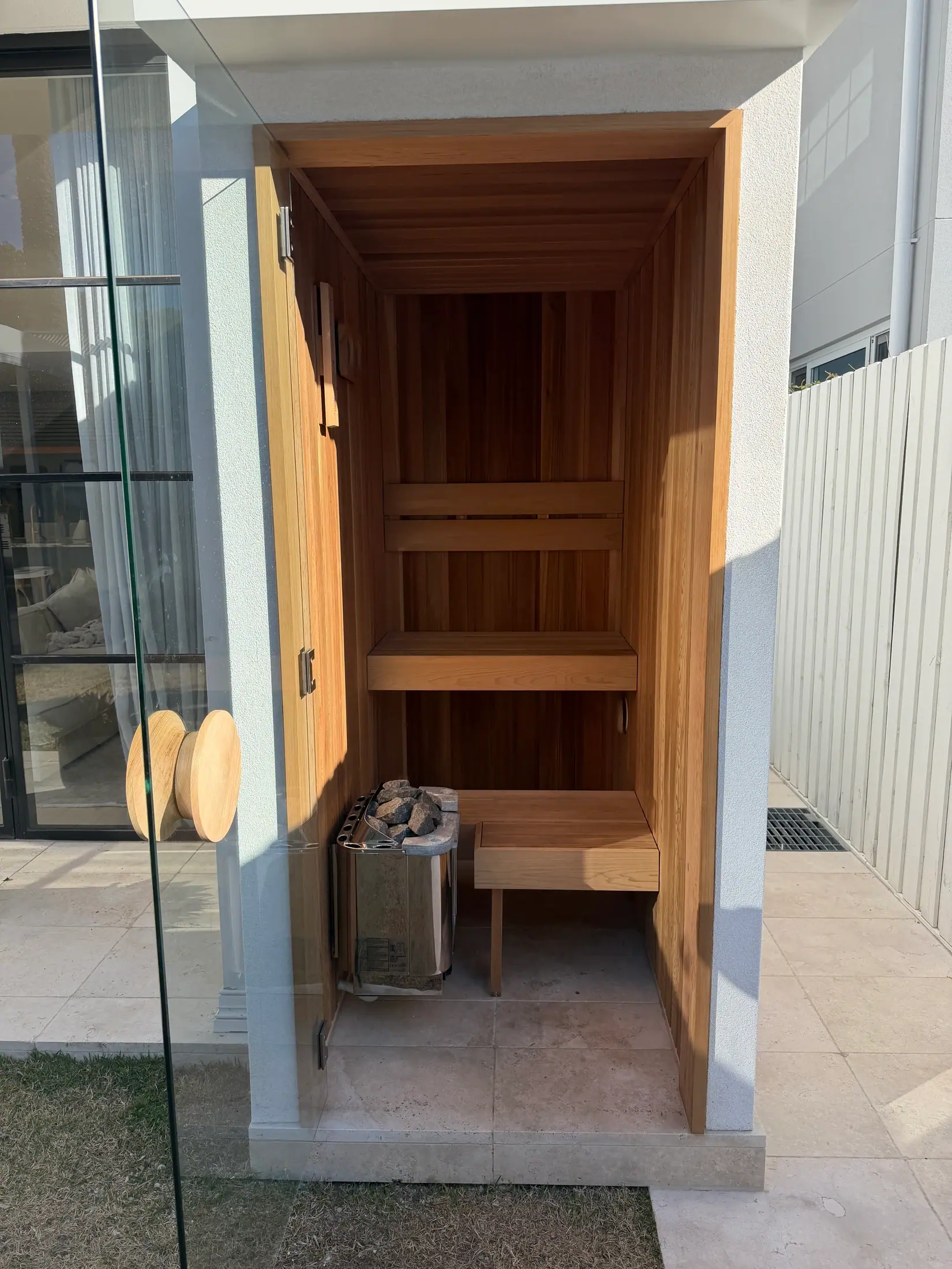 Completed custom sauna seen from the garden with its glass door open