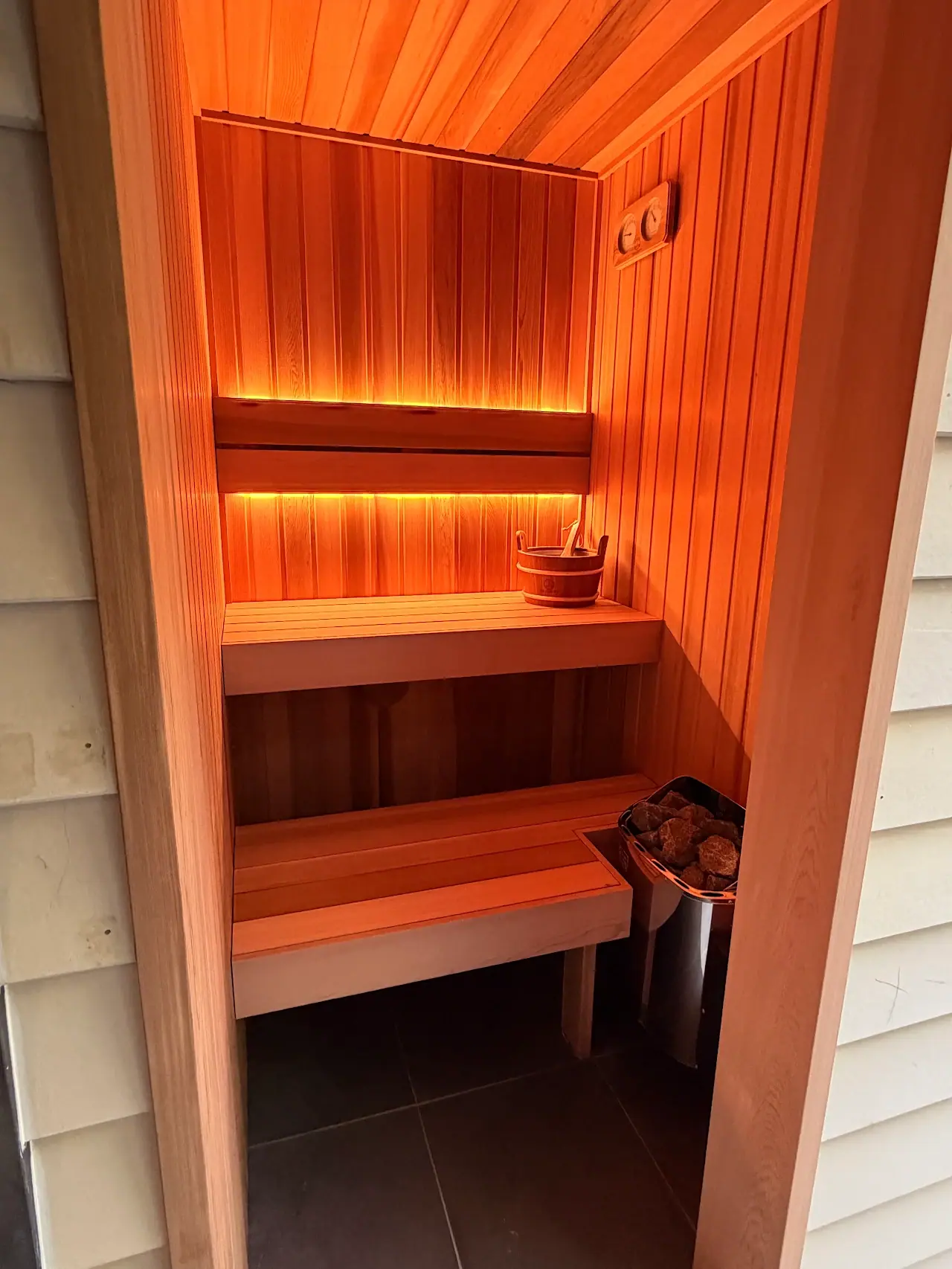 Customer photo of a lit cedar sauna interior with bench and heater