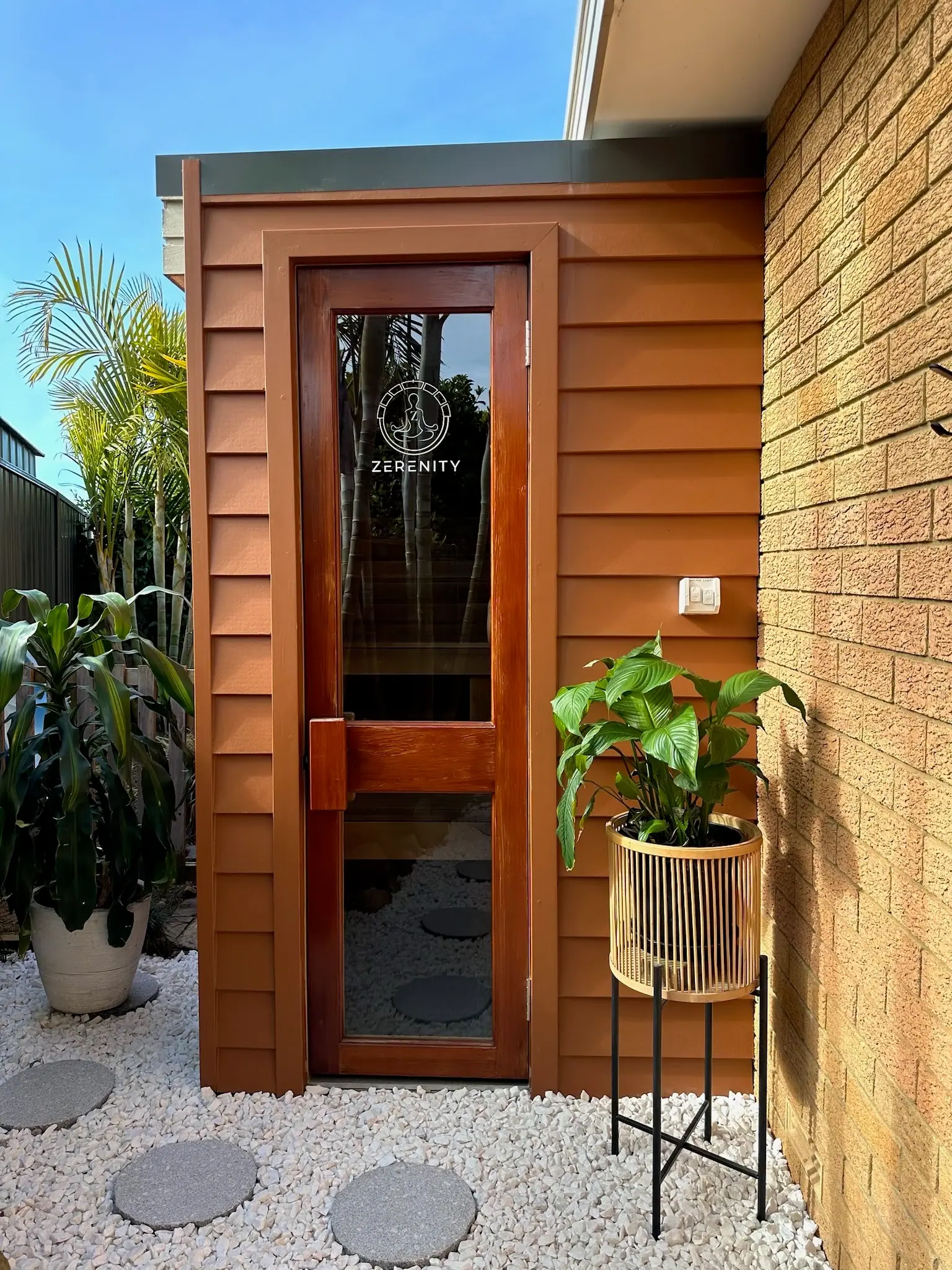 Custom cedar sauna at Jayden’s house, with a glazed door opening onto the garden path