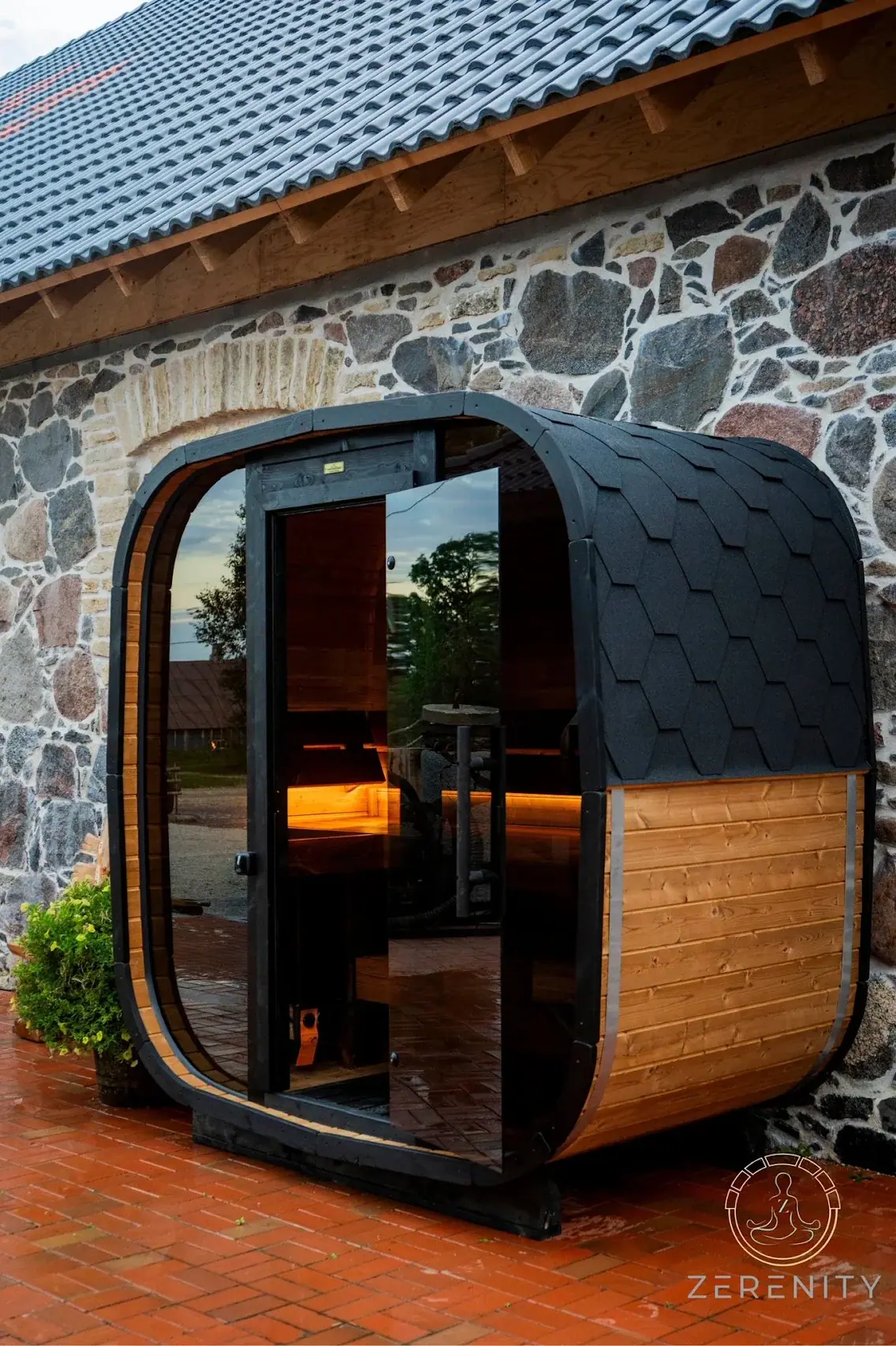 Customer photo of a Zerenity sauna installed beside a stone home