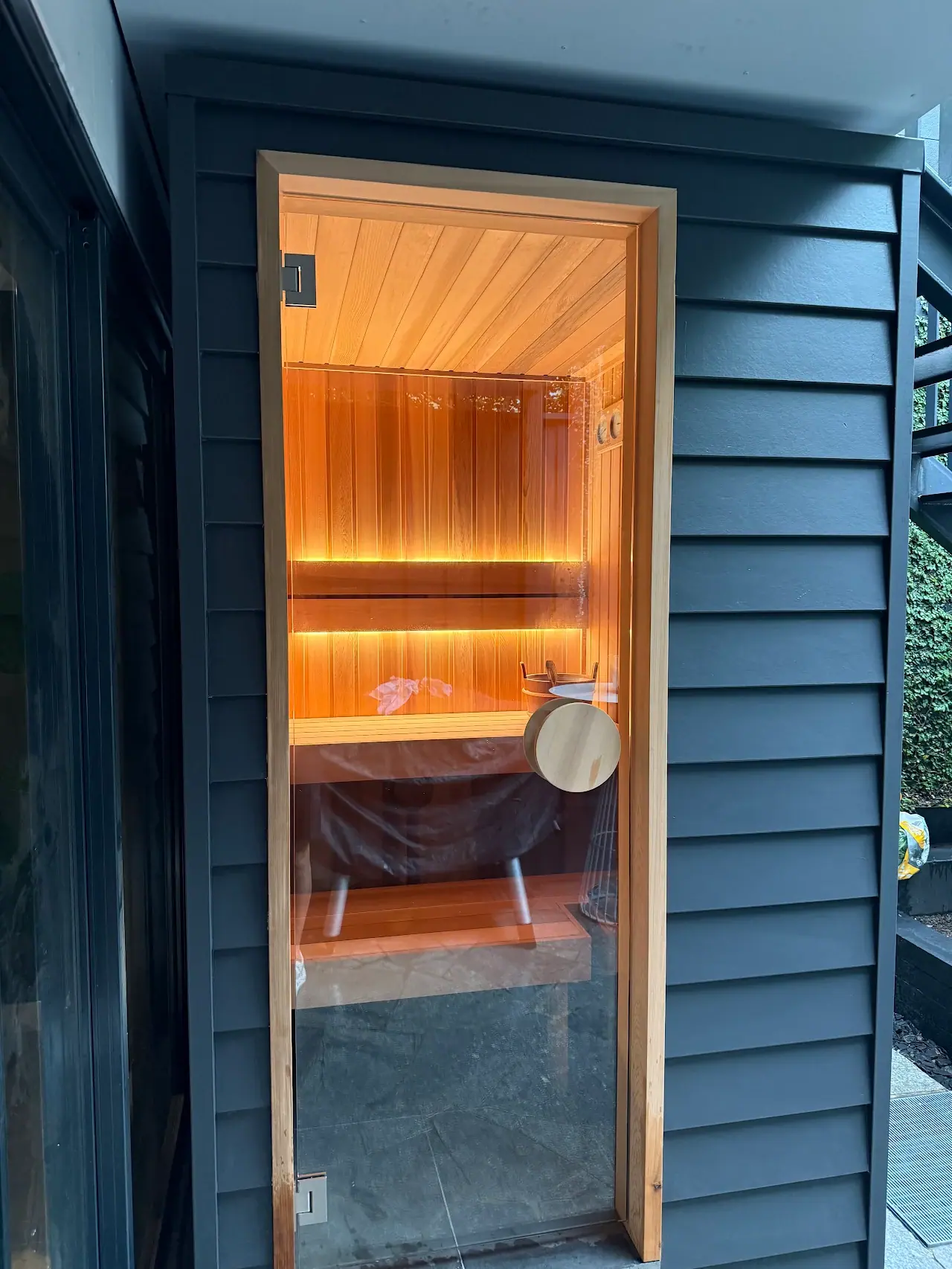 Customer photo of a Zerenity custom sauna with a full-height glass door and warm cedar interior