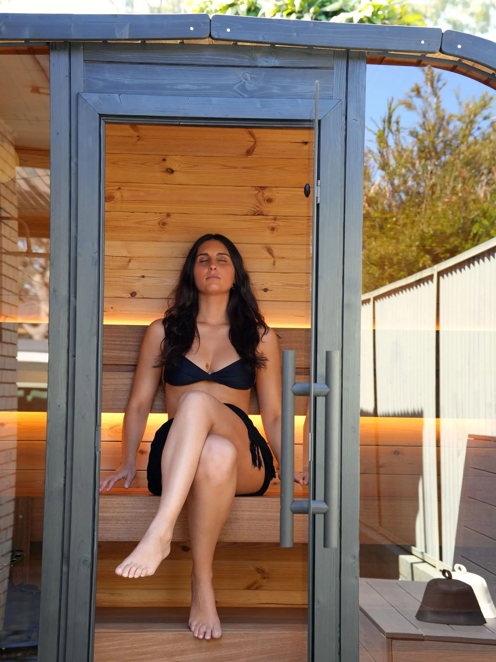 A seated sauna user inside the Koda at Mortdale, framed by the glass entrance